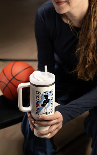 Stanley 1913 white tumbler with handle reading "Everyone Watches Women's Sports," held by a woman near a basketball.